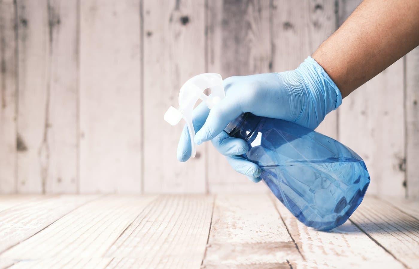 Hand in glove holding spray bottle