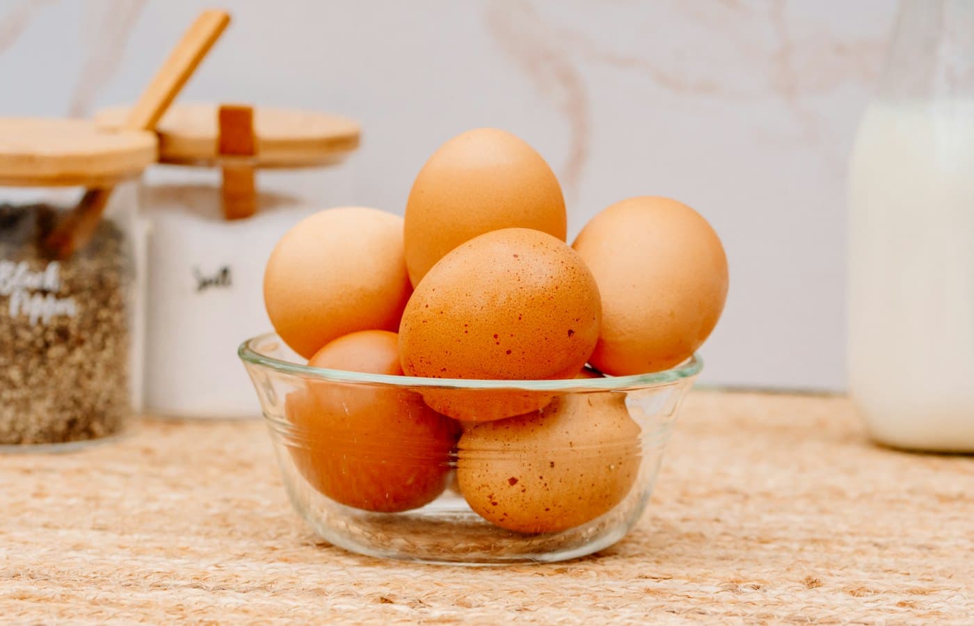 A glass bowl filled with brown eggs on top of a counter