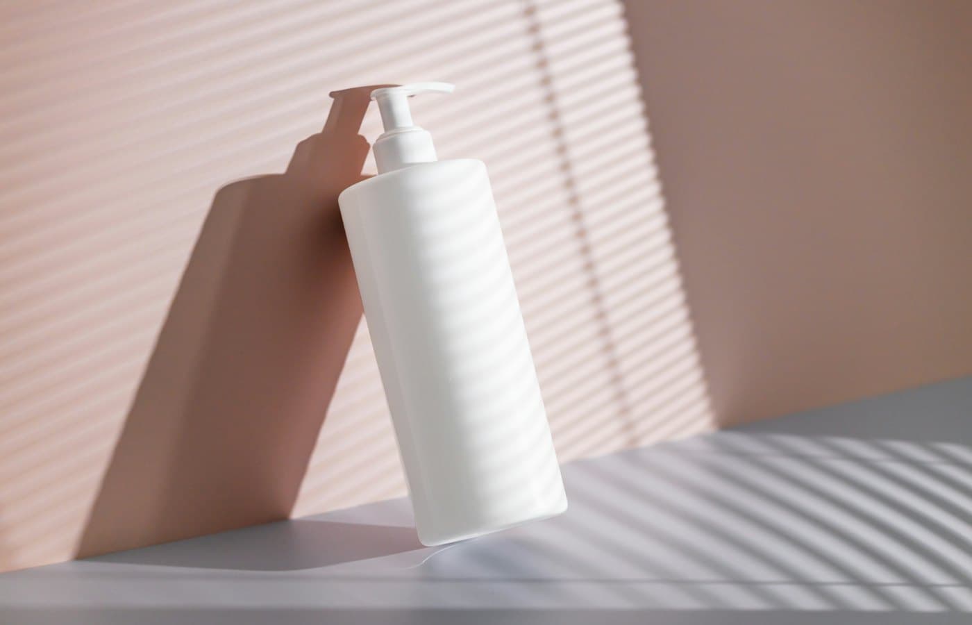 A hand holding a white bottle