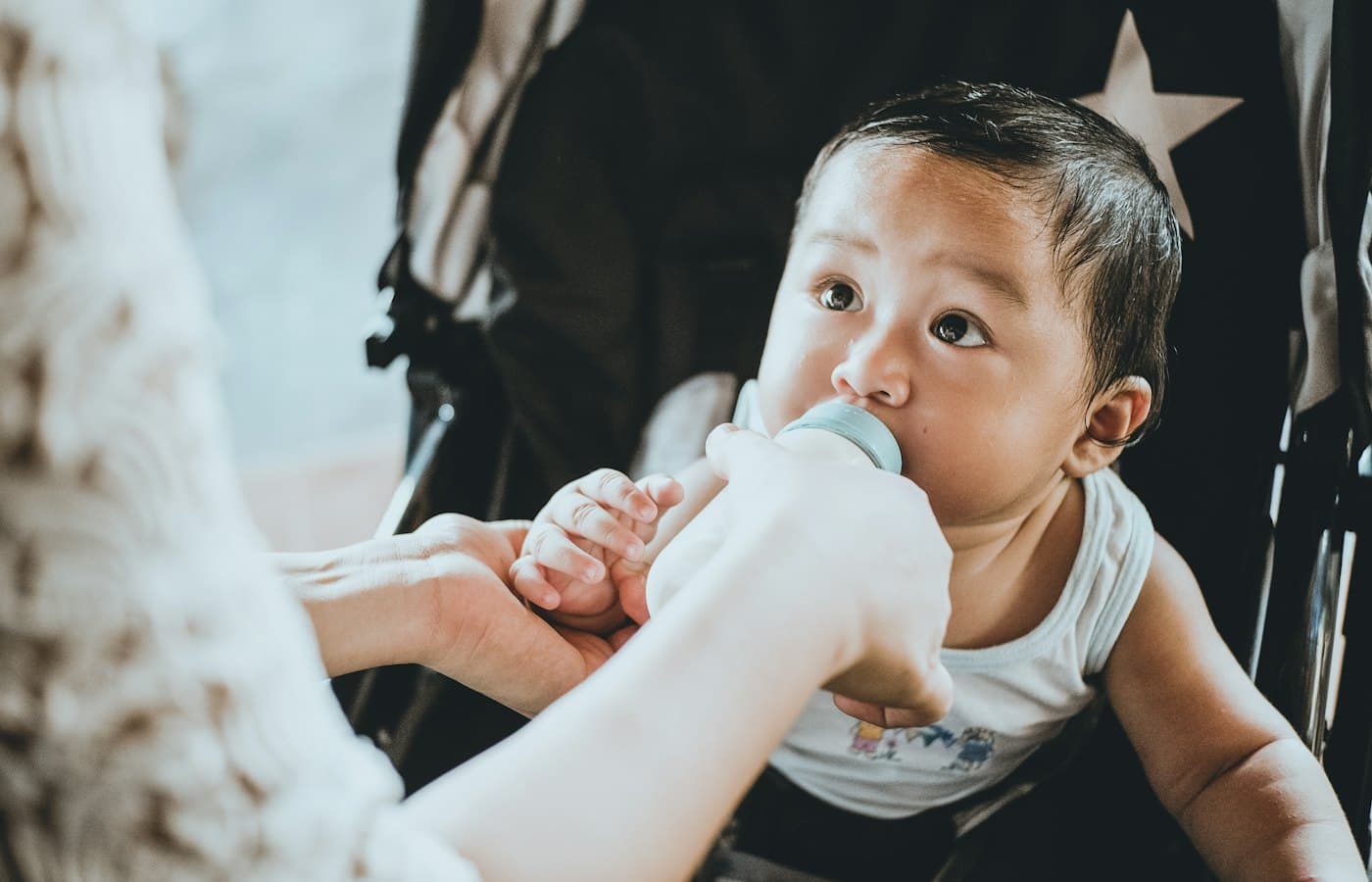 Person feeding baby from feeding bottle