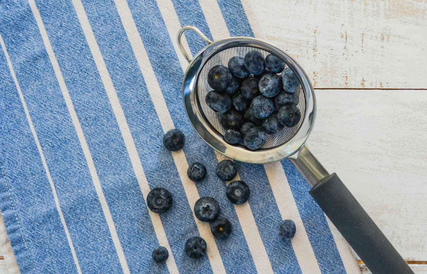 A bowl of blueberries on a blue and white towel