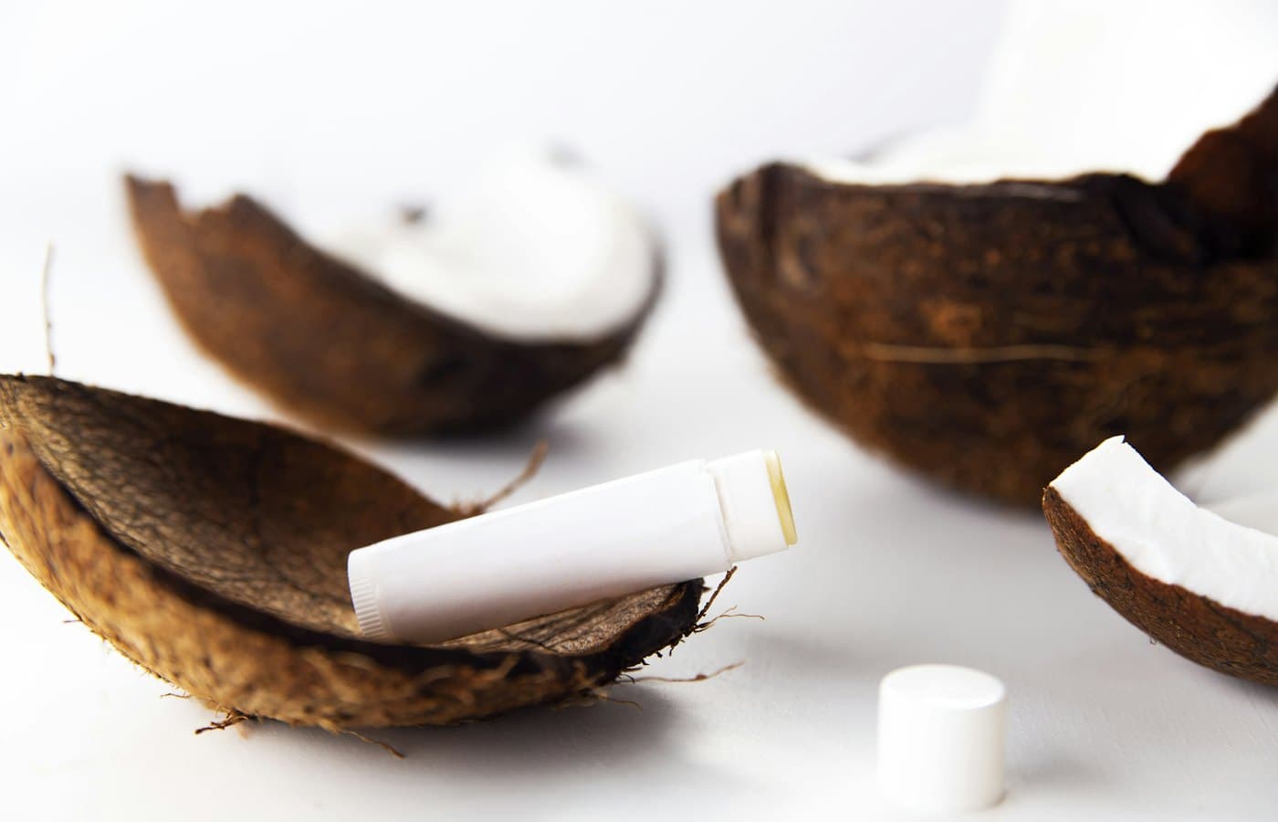 Lip balm in coconut shell halves on white background
