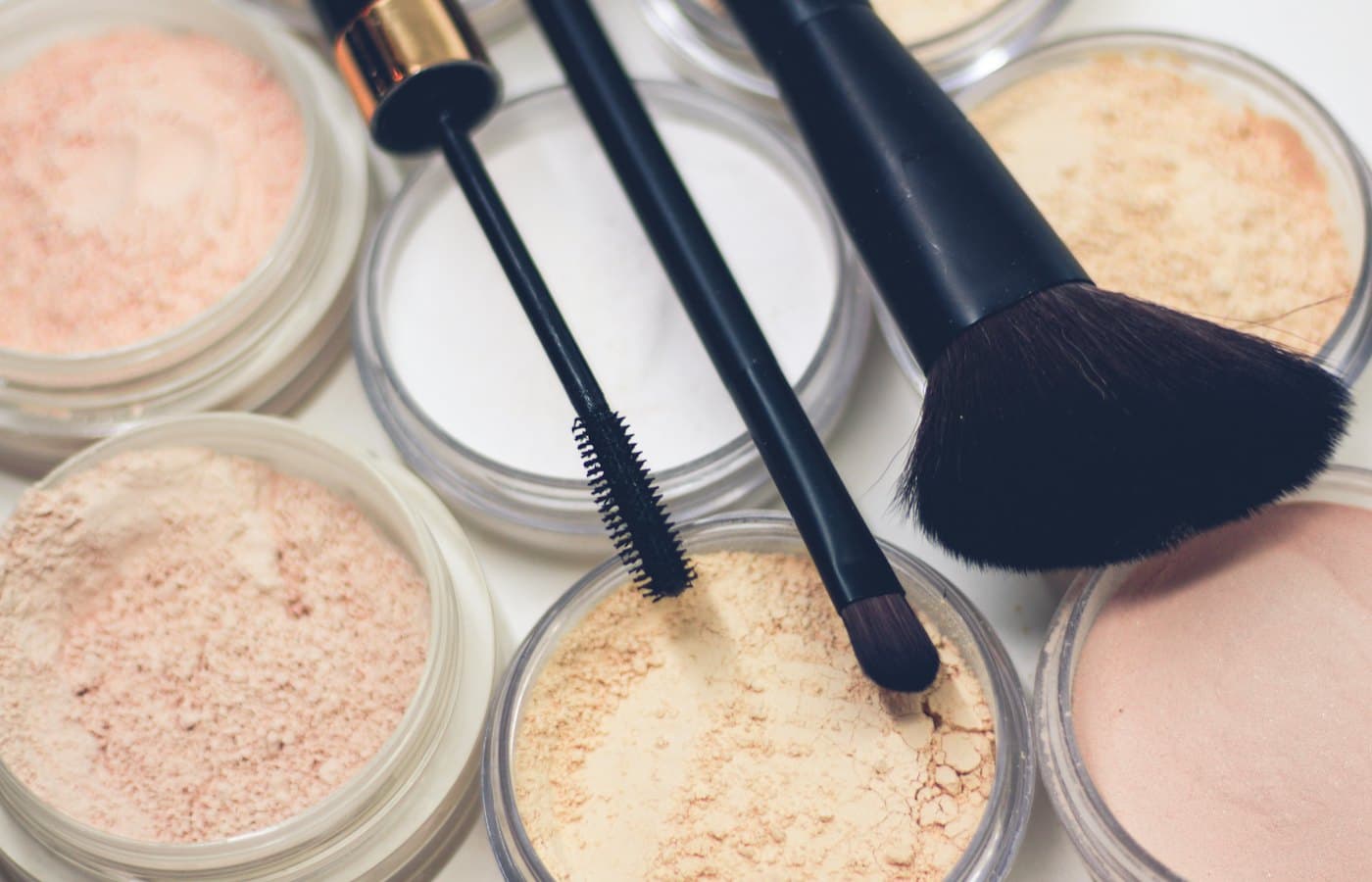 Three makeup brushes on top of compact powders