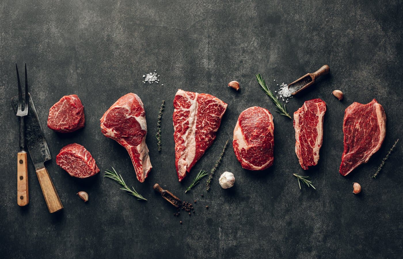 Raw meat on a table with a knife garlic and pepper