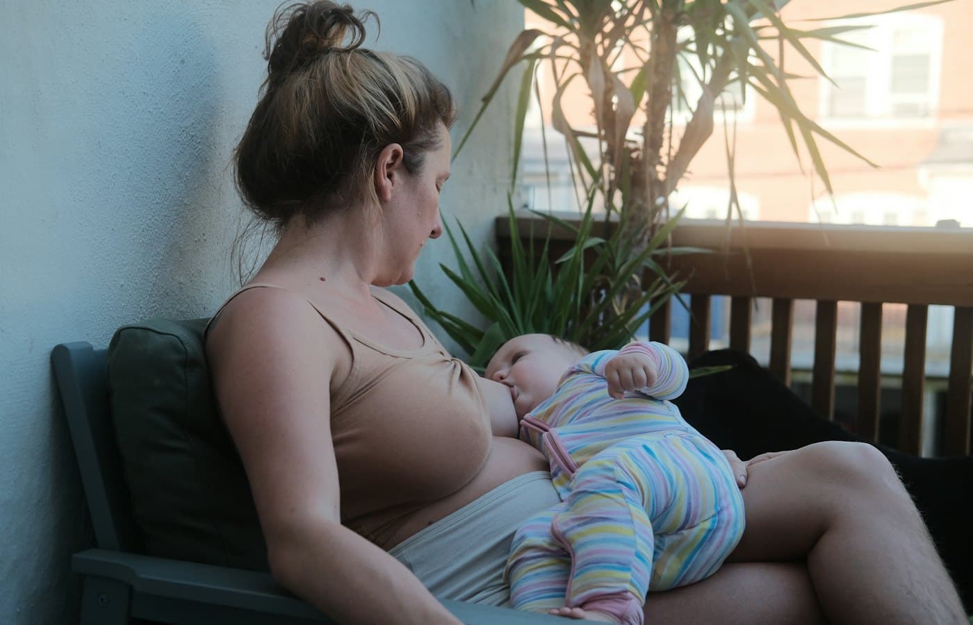 A woman sitting on a bench holding a baby