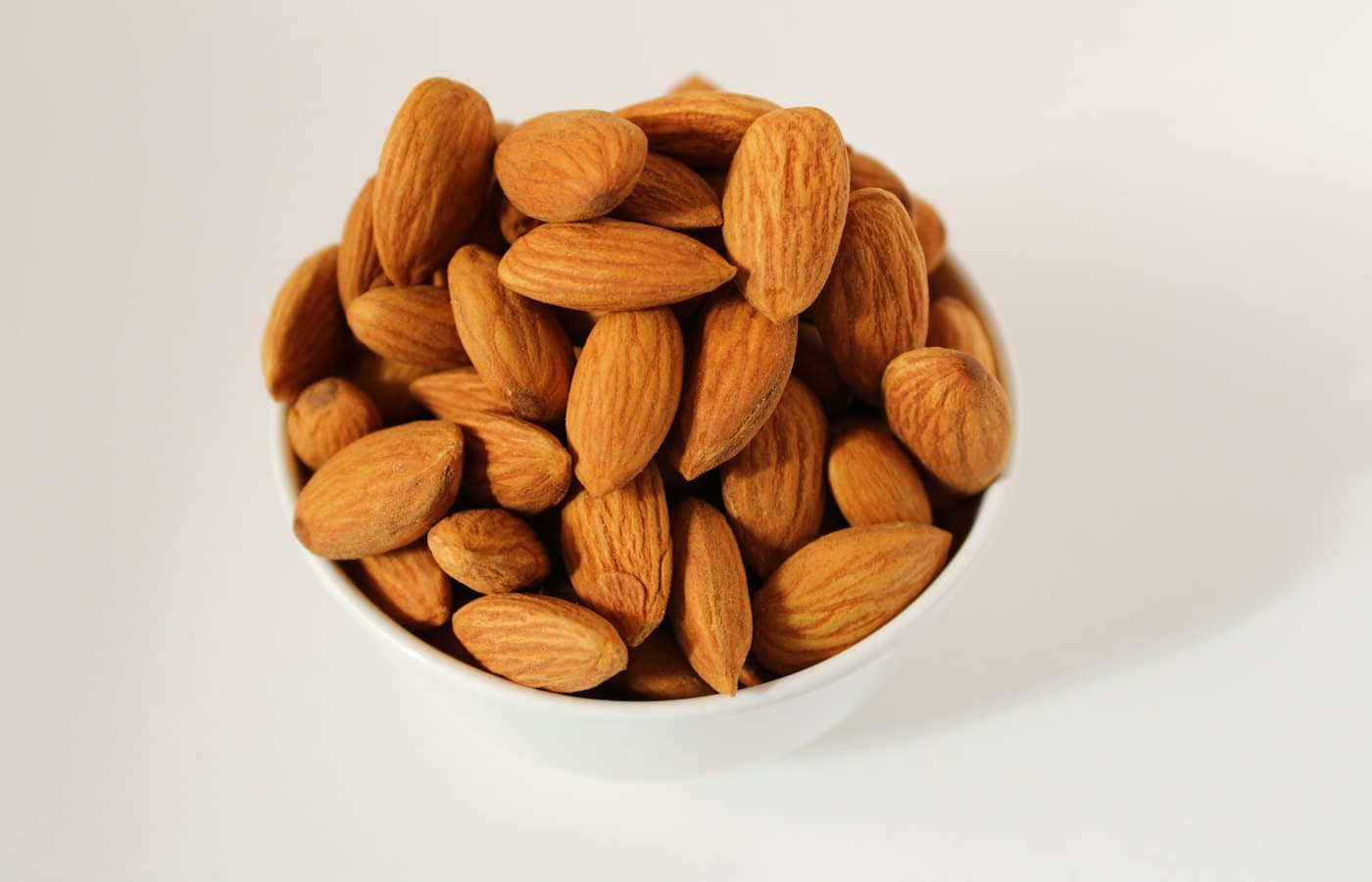 Brown almond nuts on white ceramic bowl