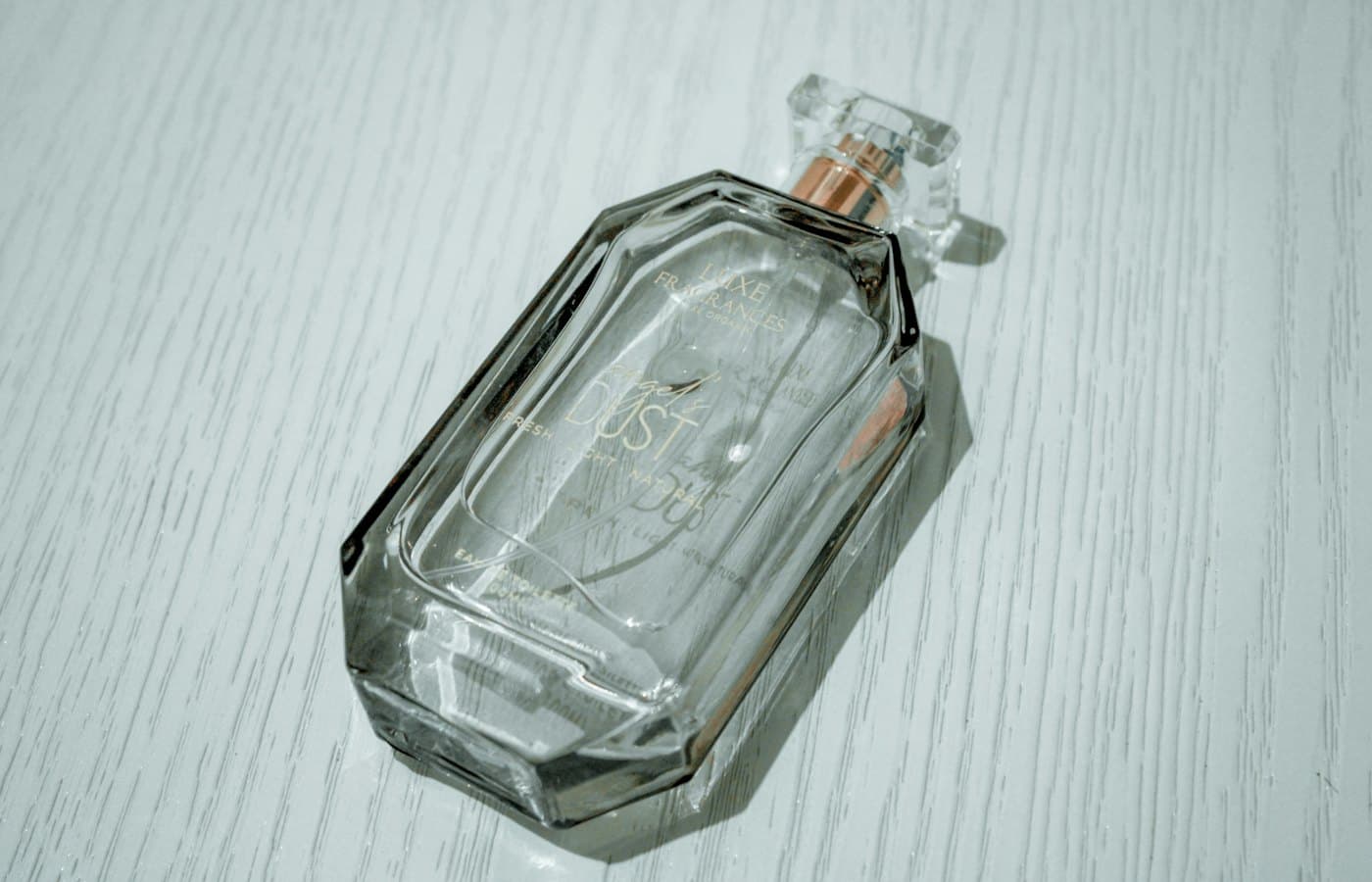A clear glass perfume bottle on a light textured surface