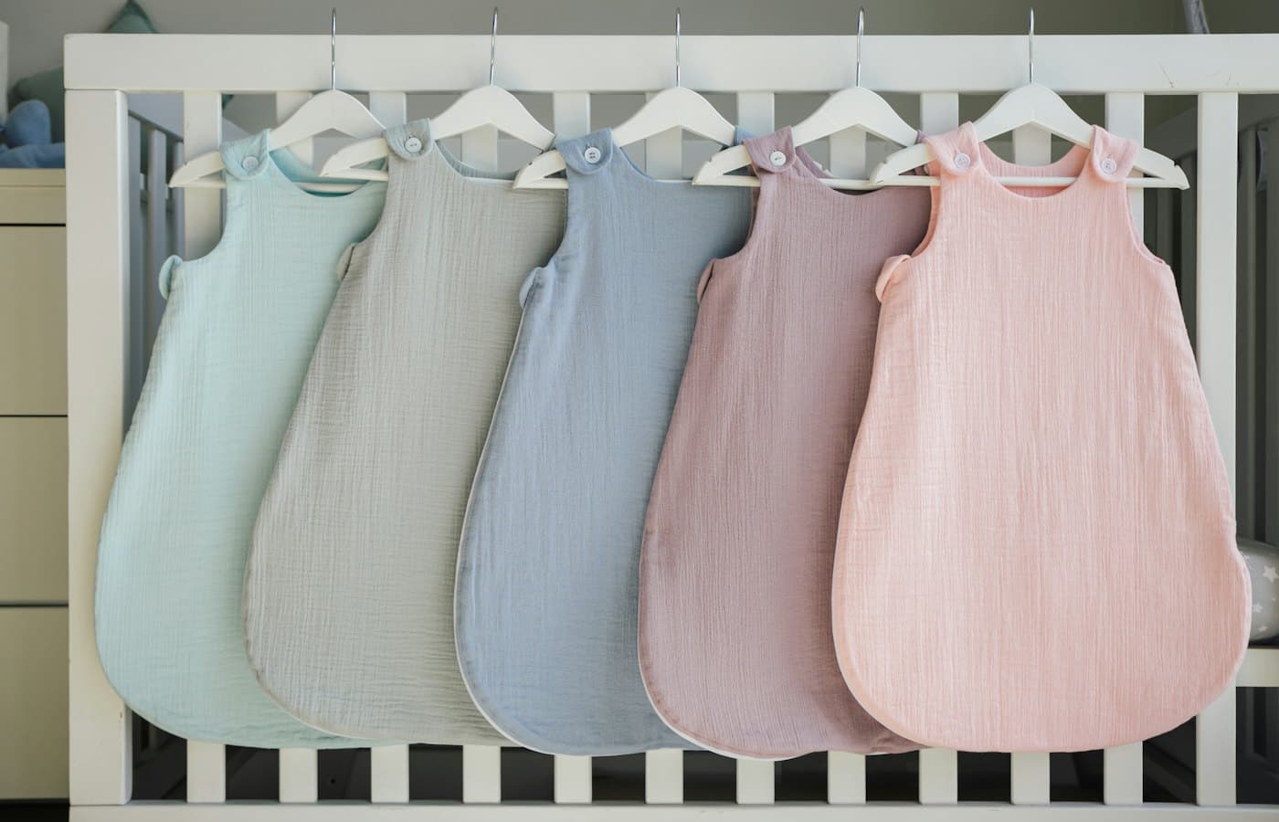 A row of baby swaddles hanging from a crib
