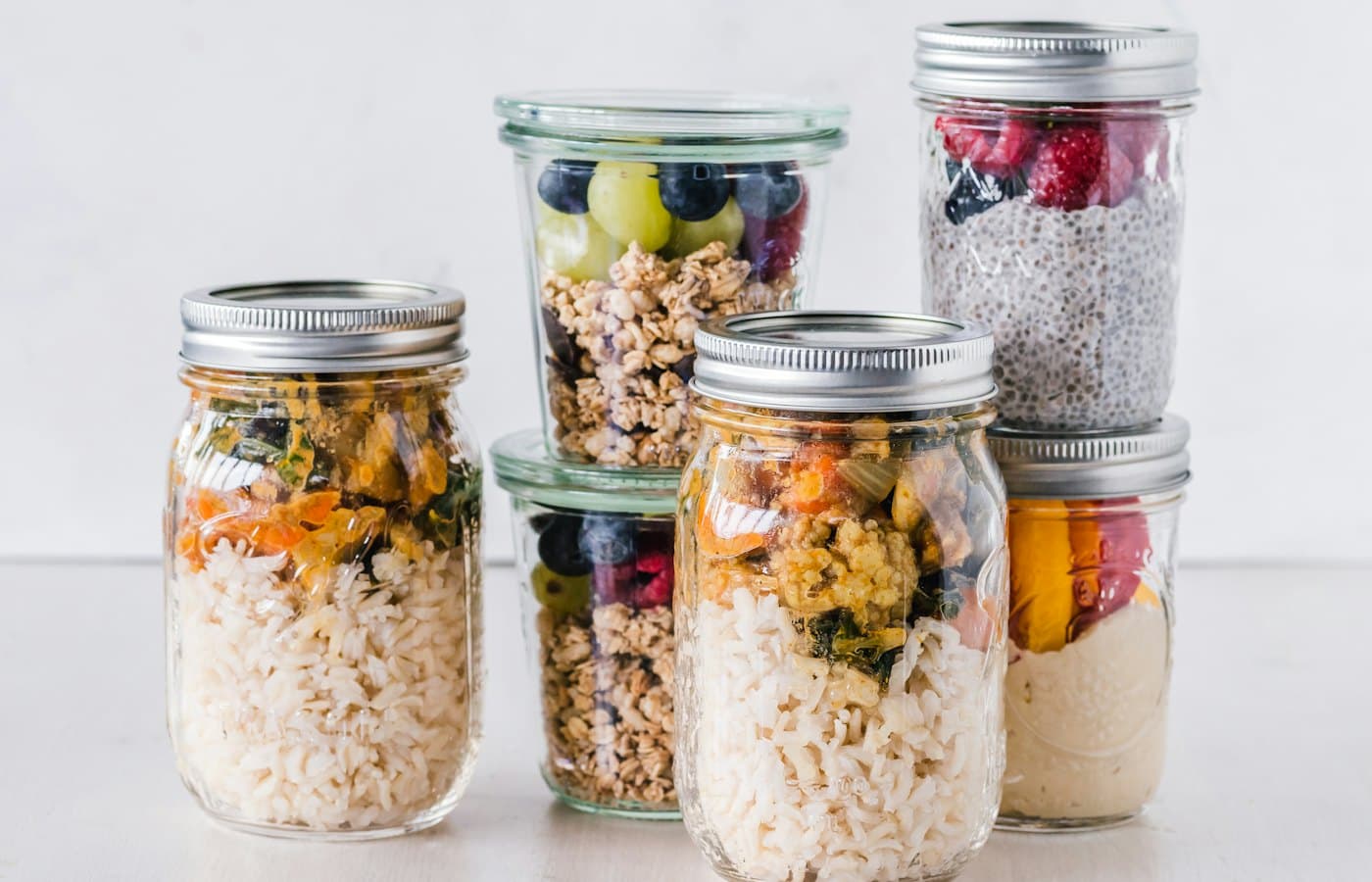 Six full clear glass jars on white surface