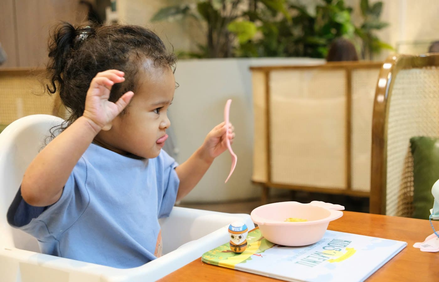Young child in high chair with spoon and bowl