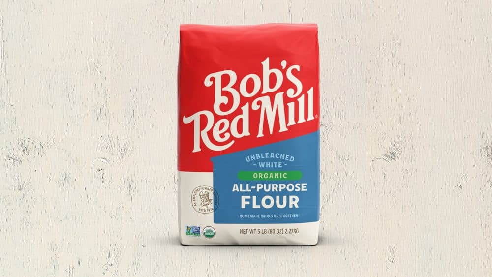 5 lb bag of Bob's Red Mill Unbleached White Organic All-Purpose Flour on a pale wood background