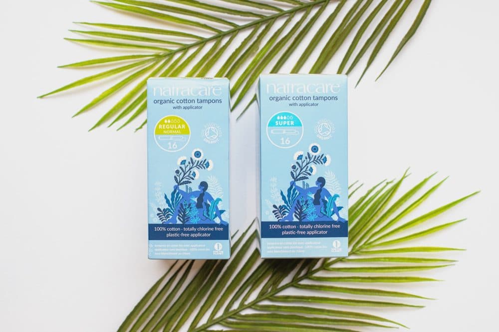 Two boxes of Natracare organic cotton tampons with applicator, Regular and Super, on palm leaves